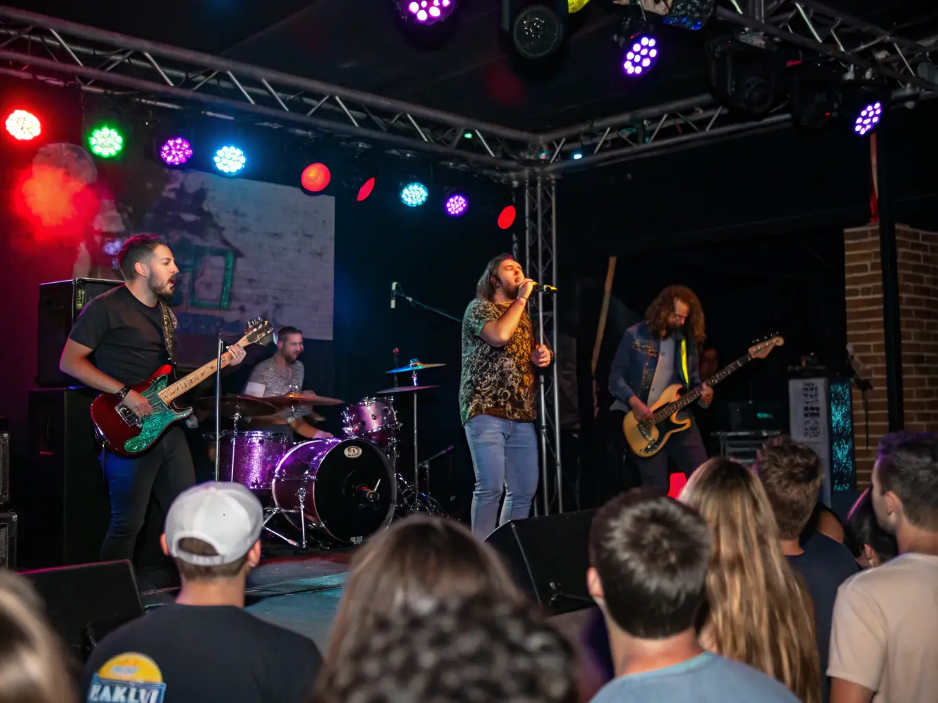 A vibrant photograph capturing a live music performance at ASSOCIATION PAARADOOBLE, showcasing a band on stage with colorful lighting and an enthusiastic audience.